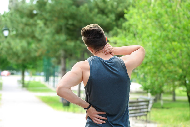 Man in sportswear suffering from back pain outdoors - Photo, Image