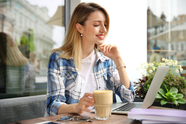 Young woman working with laptop at desk in cafe - Foto, Bild