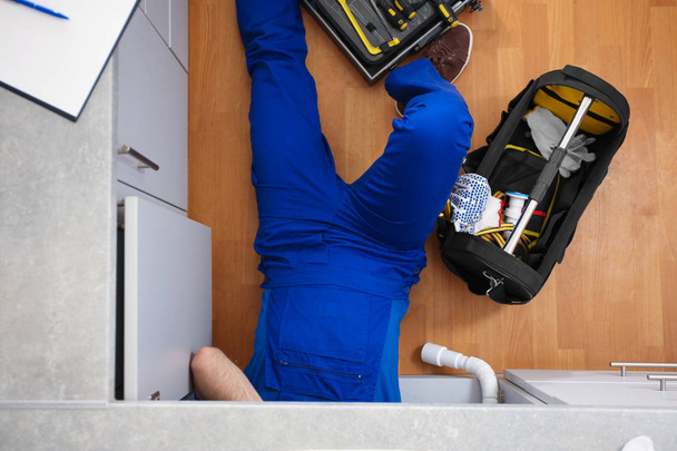 Professional plumber with set of tools working indoors, top view - Φωτογραφία, εικόνα