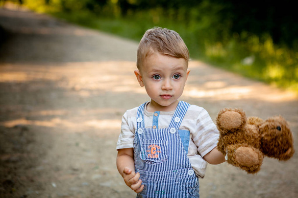 Little boy playing with teddy bear on the footpath - Photo, Image