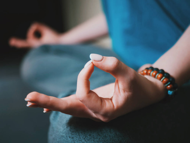 Closeup of womans hands with bracelets meditating in lotus pose indoors. Gyan mudra. Yoga, religion concept. - Fotoğraf, Görsel