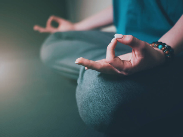 Closeup of womans hands with bracelets meditating in lotus pose indoors. Gyan mudra. Yoga, religion concept. - Foto, Imagem