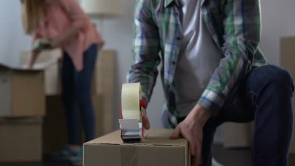 Young couple packing their things in boxes, moving from dormitory to own house - Materiał filmowy, wideo