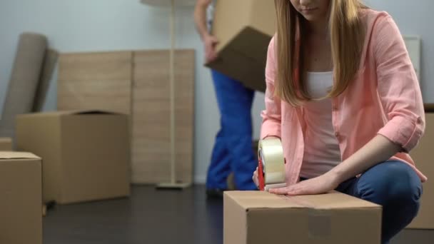 Lady packing things in box, moving company worker carrying baggage, moving out - Video