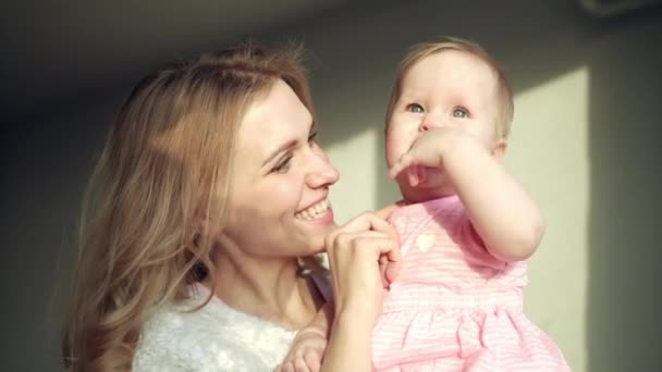 Happy mother holding baby girl on hands. Cheerful mom embrace toddler girl - Footage, Video