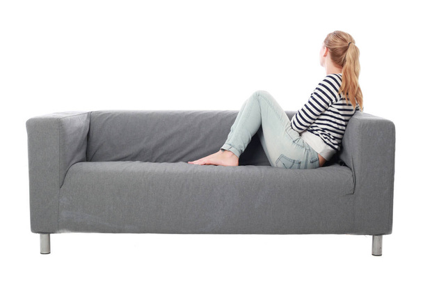 ritratto di una ragazza seduta su un divano grigio, isolata su uno sfondo bianco
. - Foto, immagini