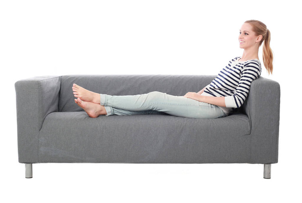 retrato de longitud completa de la niña sentada en un sofá gris, aislado en el fondo blanco del estudio
. - Foto, imagen