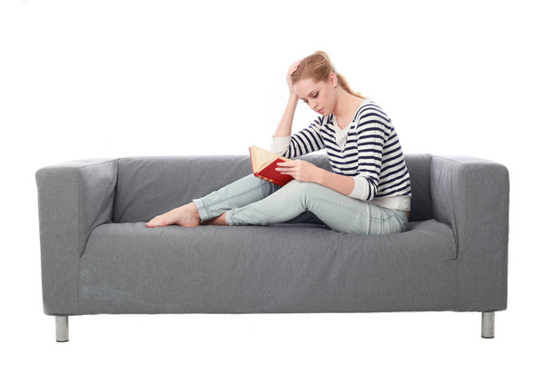 ritratto di una ragazza seduta su un divano grigio, isolata su uno sfondo bianco
. - Foto, immagini