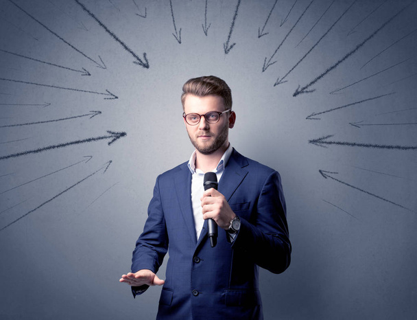 Businessman speaking into microphone with arrows pointing towards his head - Foto, imagen