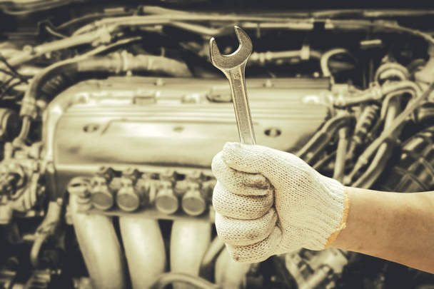 Hand holding wrench on blur car engine background - Photo, Image