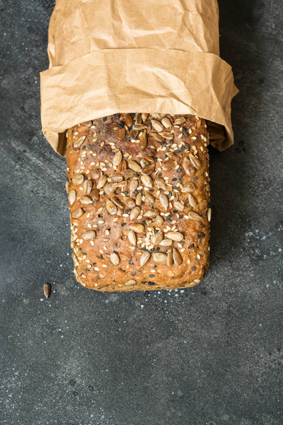 Homemade fresh rye bread with sunflower seeds on dark rural background. Close up. Space for text. - Фото, изображение