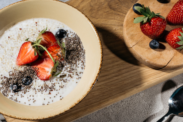Здоровый завтрак с чашей с семенами чиа и ягодами на деревянном столе
 - Фото, изображение