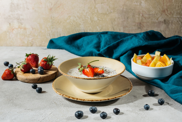 Café da manhã saudável com chia sementes tigela e frutas maduras na mesa com toalha de mesa
 - Foto, Imagem