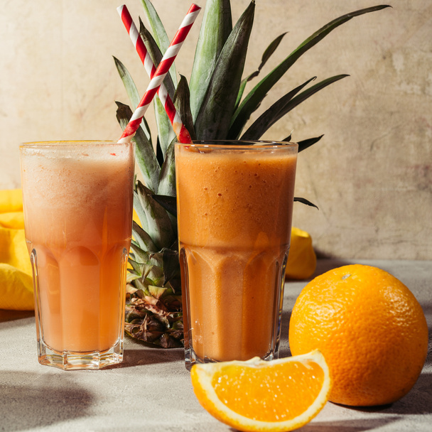 Тропические фрукты и стаканы с соком на столе
 - Фото, изображение