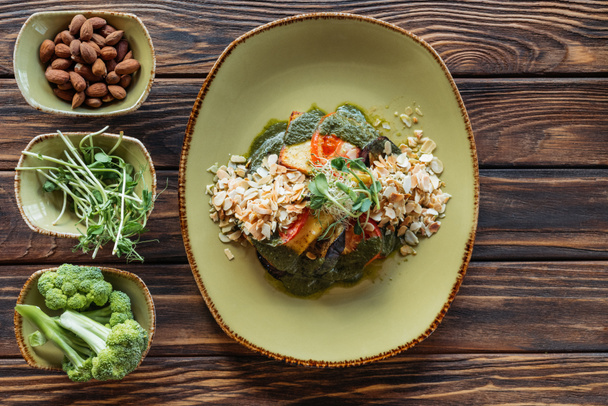vista superior de la ensalada vegetariana servida en plato e ingredientes frescos en cuencos sobre mesa de madera
 - Foto, Imagen