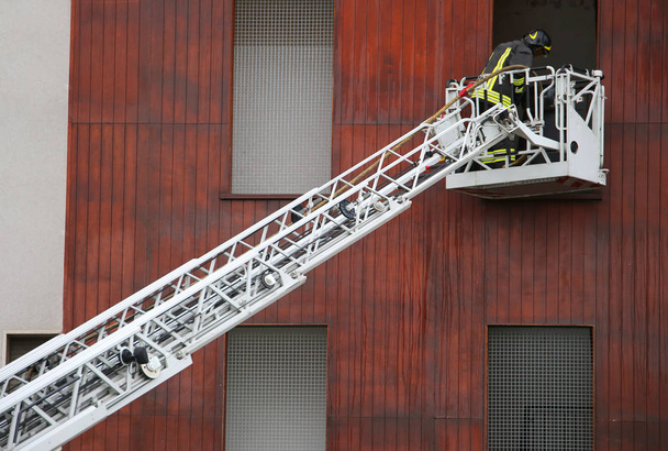 lange antenne ladder en brandweerlieden tijdens een noodsituatie - Foto, afbeelding