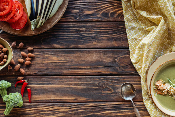 ahşap yüzeyde vejetaryen krem çorbası, taze sebze ve badem üstten görünüm - Fotoğraf, Görsel