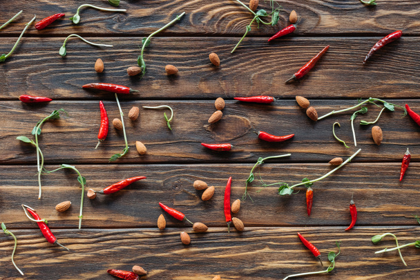 full frame of arranged chili peppers, almonds and sprouts on wooden tabletop - Photo, Image