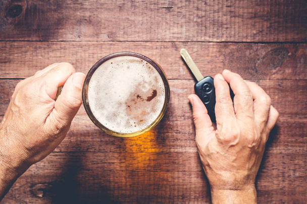 Hombre mano bebiendo cerveza y sosteniendo las llaves del coche
 - Foto, Imagen