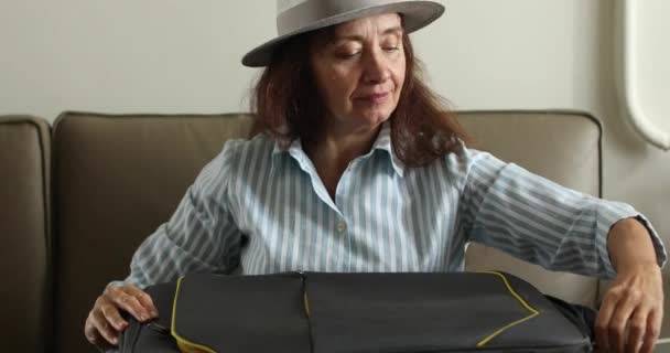 Elderly woman is going on vacation packing a suitcase - Footage, Video