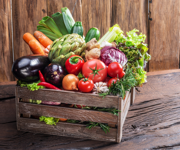 Fresh multi-colored vegetables in wooden crate. Wooden background. - Photo, Image