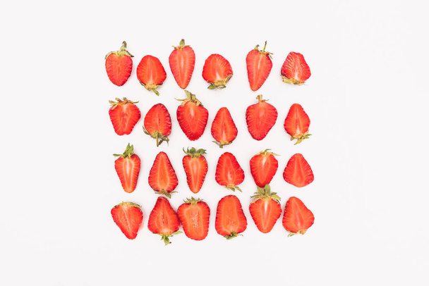 bovenaanzicht van vers gesneden aardbeien in rijen geïsoleerd op witte achtergrond - Foto, afbeelding