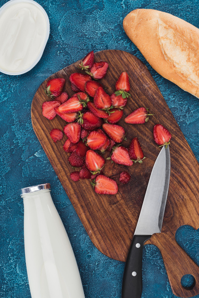 Cutting fresh strawberries on table with bread and milk - Foto, Imagen