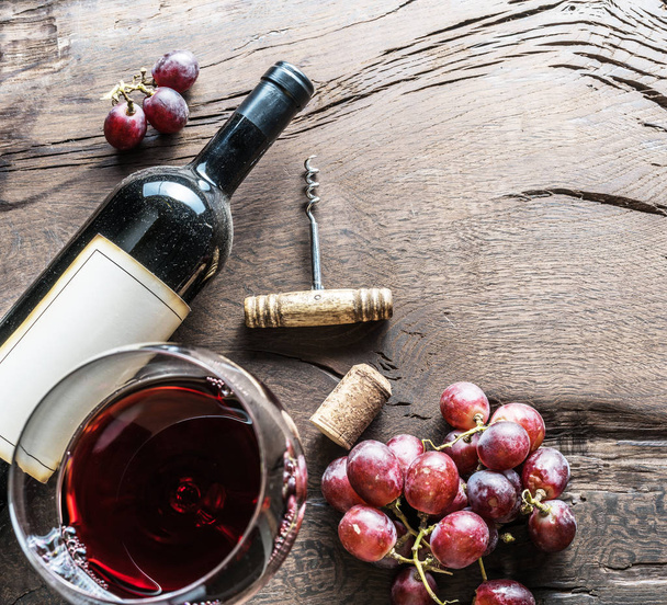 Borospohár, a borosüveg és a szőlő, a fából készült háttér. Borkóstolás. - Fotó, kép