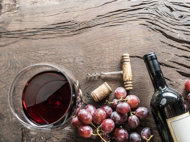 Viinilasi, viinipullo ja viinirypäleet puupohjalla. Viininmaistelu
. - Valokuva, kuva
