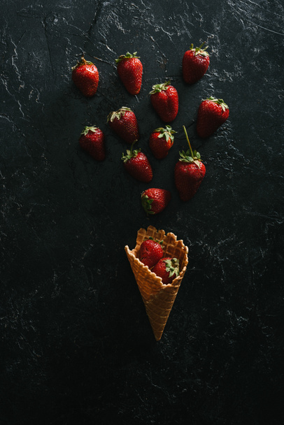 vista superior de morangos vermelhos por cone de waffle no fundo escuro
 - Foto, Imagem