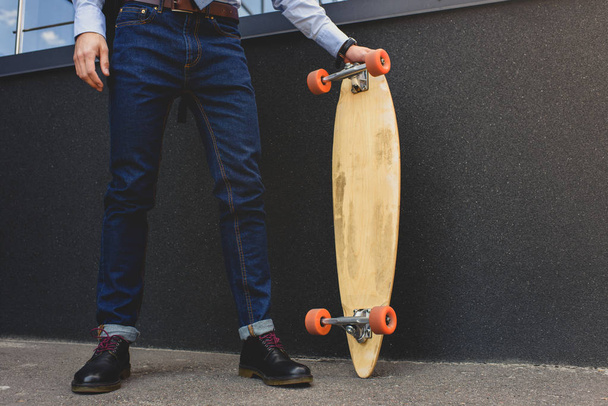 low section of stylish man standing on longboard on street    - Photo, Image