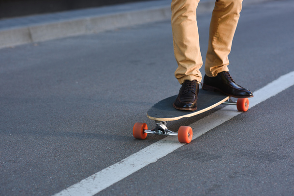 cropped shot of young man standing on skateboard on street  - Fotoğraf, Görsel