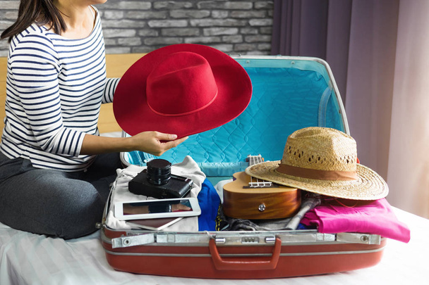 Seyahat ve tatil kavramı, mutluluk genç kadın elbiselerini ve malzeme bir sürü bavul yatak içine ambalaj tatil seyahat ve yolculuk yolculuk için hazırlamak. - Fotoğraf, Görsel