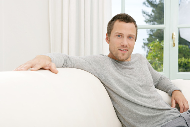 Young businessman relaxing on a white sofa at home - Photo, Image