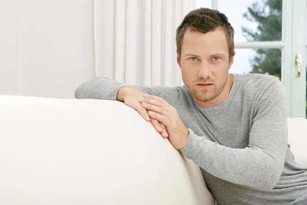Young businessman relaxing on a white sofa at home. - Foto, Bild