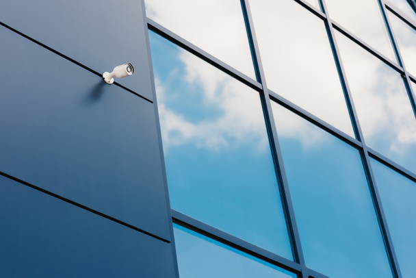 Façade en verre de l'immeuble de bureaux moderne avec caméra de sécurité et nuages réfléchis
 - Photo, image