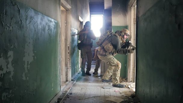 Sotilaat naamioituneina taisteluaseilla hiippailevat vanhan rakennuksen käytävillä, sotilaskonsepti
 - Valokuva, kuva