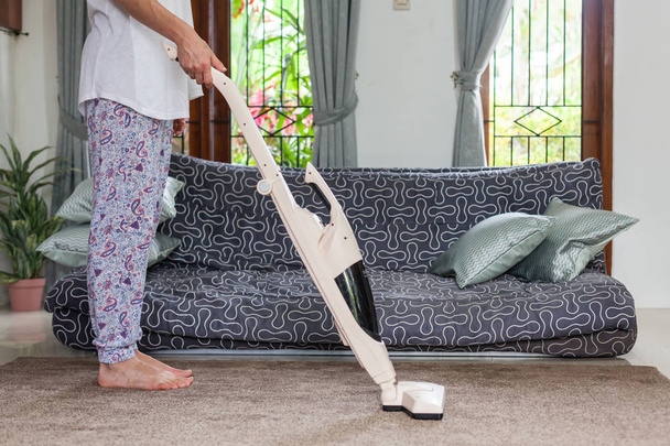 Fiatal nő használ egy porszívó a ház szőnyeg takarítás közben. - Fotó, kép