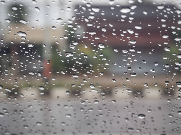 Вид на дорогу через лобовое стекло автомобиля с капельками дождя, вождение под дождем
. - Фото, изображение