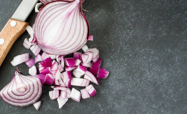 A flat lay image of chopped red onions on a dark stone surface with copy space for your text - Foto, Imagen