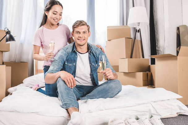 boldog, fiatal pár ül ágyas pezsgővel után beköltöző új otthonában - Fotó, kép
