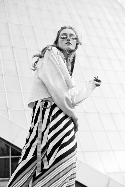 Black and white photo of attractive  young woman in stylish eyeglasses posing outdoors - Foto, imagen