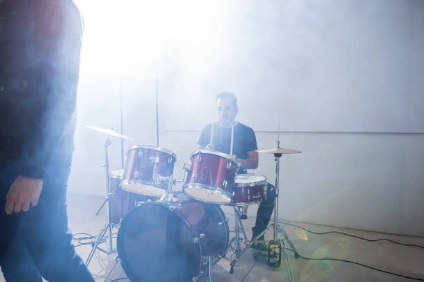 Rock drummer van de band in actie op het podium met verlichting en rook - Foto, afbeelding