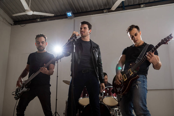 Laulaja kitaristien kanssa esiintymässä rock and roll musiikkia lavalla musiikkifestivaaleilla
 - Valokuva, kuva