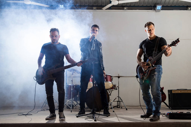 Группа рок-н-ролла выступает на сцене с огнями и дымом за спиной
 - Фото, изображение