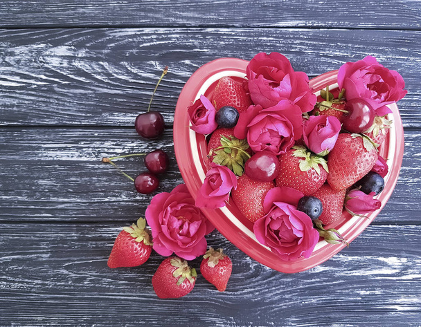 клубника, вишня, черника пластины сердца, цветок розы на черном деревянном фоне
 - Фото, изображение