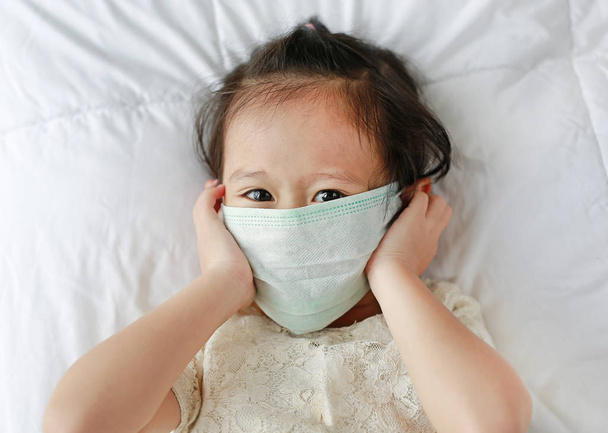 little girl wearing a protective mask lying on the bed. - Foto, immagini