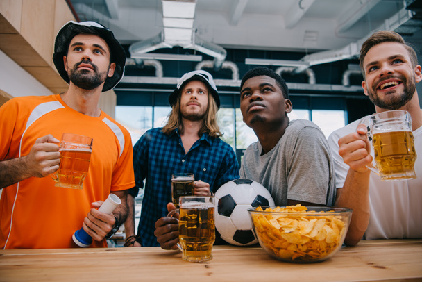 concentrated multicultural group of male football fans with beer watching soccer match at bar - Photo, Image