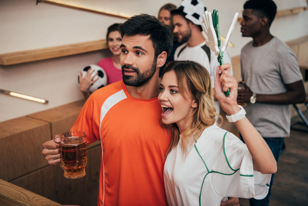 pareja y sus amigos multiculturales viendo el partido de fútbol en el bar
  - Foto, Imagen
