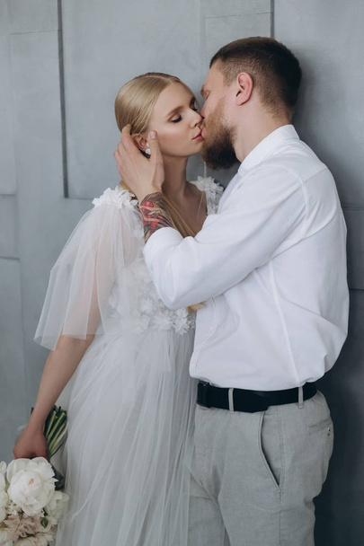 elegáns fiatal menyasszony és a vőlegény csók előtt szürke fal - Fotó, kép
